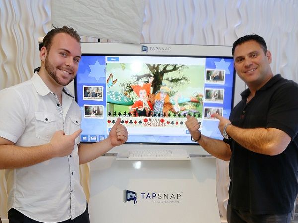 Michael Rozen, owner of TapSnap 1153, shows off his kiosk with a member of his event entertainment team.